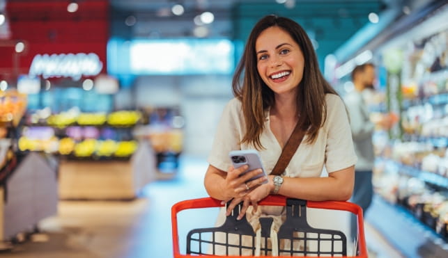 Woman food shopping while checking her phone